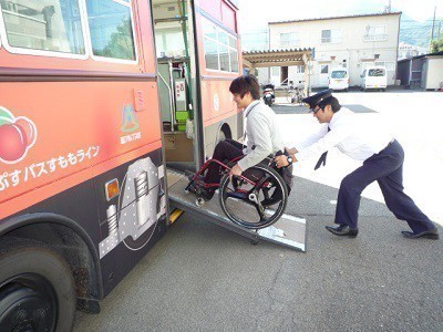 バスのスロープを使用し、運転手が介助して車椅子でバスの乗り込む写真